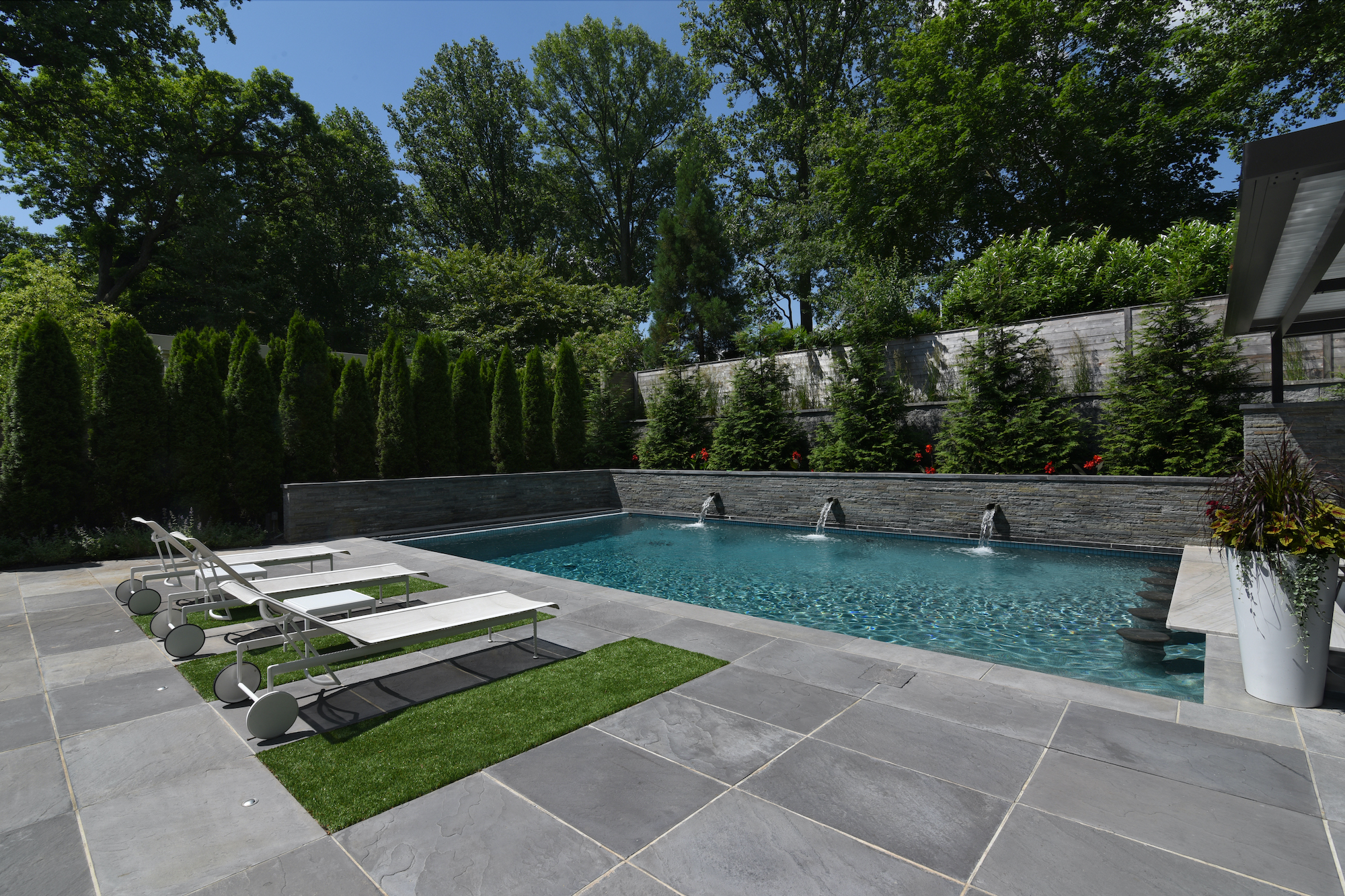 Wet-cast stone pool deck. Astro-turf, pool with water features. Bond beam wall and screening trees.